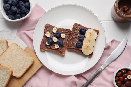 Different tasty toasts with nut butter and products on white wooden table, flat layの写真素材