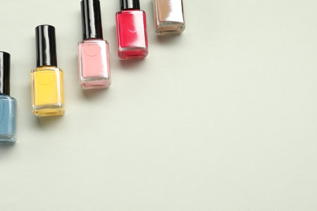 Colorful nail polishes in bottles on light background, flat lay. Space for textの写真素材