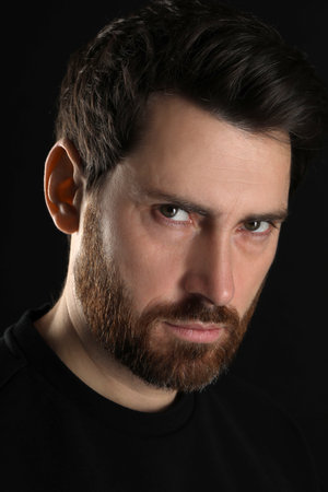 Evil eye. Man with scary eyes on black background, closeupのeditorial素材