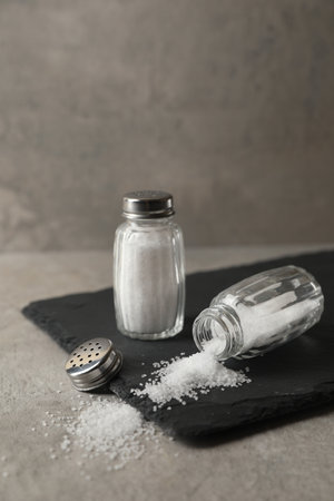 Natural salt in shakers on gray table