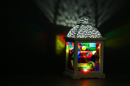 Decorative Arabic lantern on table against dark background. Space for textの写真素材