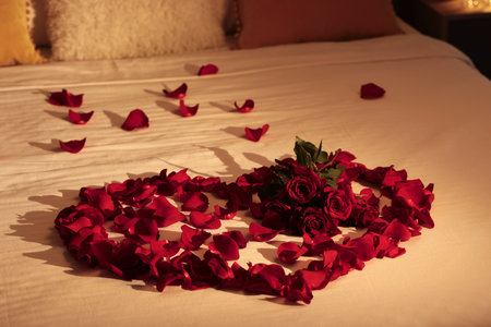 Honeymoon. Heart made with roses and beautiful petals on bedの写真素材