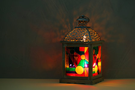 Decorative Arabic lantern on table against dark background. Space for text