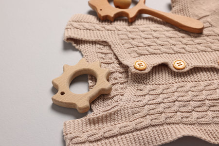 Baby accessories. Wooden rattle, teether and knitted cloth on gray background, closeup