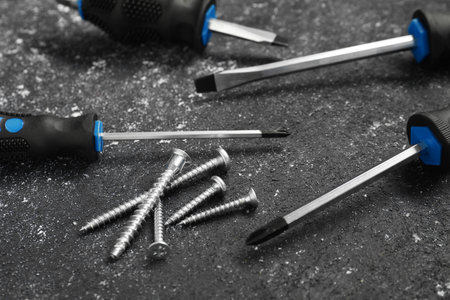 Set of screwdrivers and screws on gray table, closeup