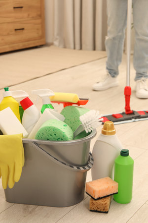 Different cleaning supplies in bucket and woman mopping floor, selective focusの写真素材