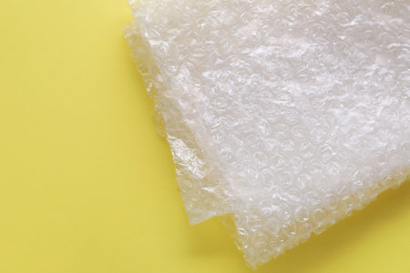 Transparent bubble wrap on yellow background, top view. Space for textの写真素材