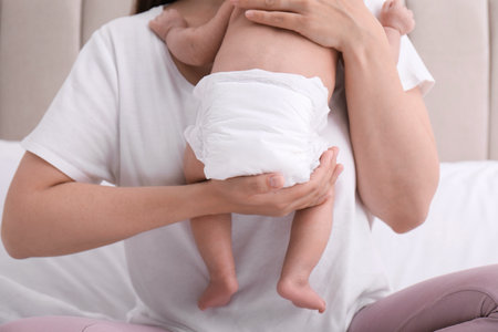Mom holding her baby in diaper at home, closeupの写真素材