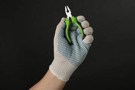 Man with combination pliers on black background, closeupの写真素材