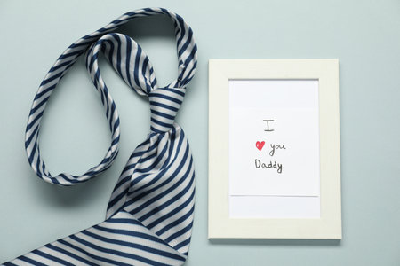 Father's day celebration. Photo frame with phrase I Love You Daddy and necktie on gray background, flat layの写真素材