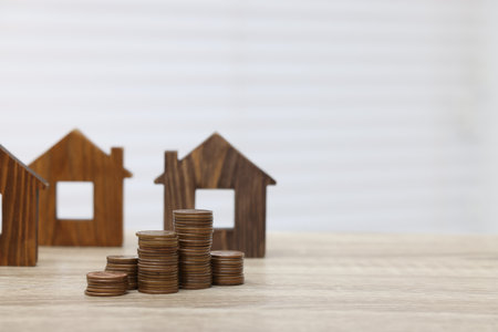 House models and stacked coins on wooden table, space for textの写真素材