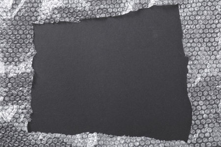 Frame made of pooping wrap on black background, top view. Space for text