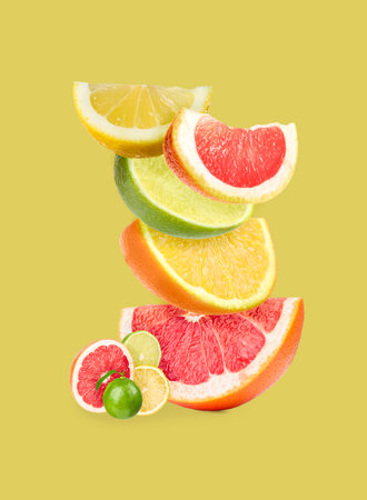 Stack of different citrus fruits on pale yellow backgroundの写真素材