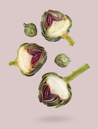 Fresh raw artichokes falling on light gray backgroundの写真素材