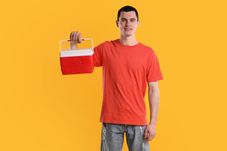 Man with red cool box on orange backgroundの写真素材