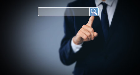 Man pointing at search bar on virtual screen against dark background, closeup. Banner designの写真素材