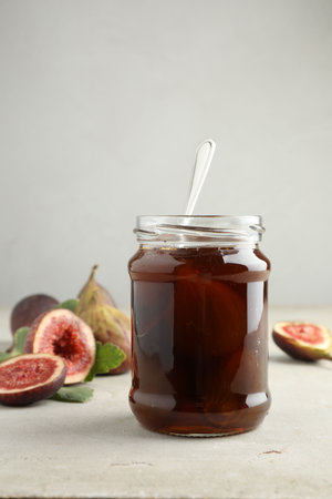 Jar of tasty sweet fig jam on light tableの写真素材