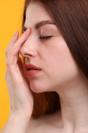 Portrait of beautiful woman with freckles on yellow background, closeupの写真素材