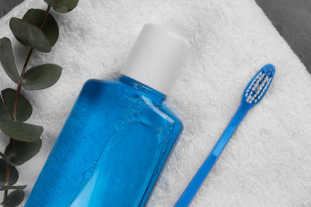 Fresh mouthwash in bottle, toothbrush, eucalyptus branch and towel on table, top viewの写真素材