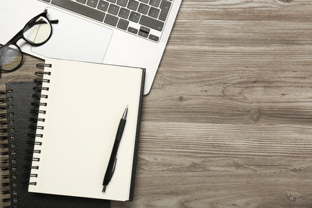 Flat lay composition with notebooks and laptop on wooden table, space for text