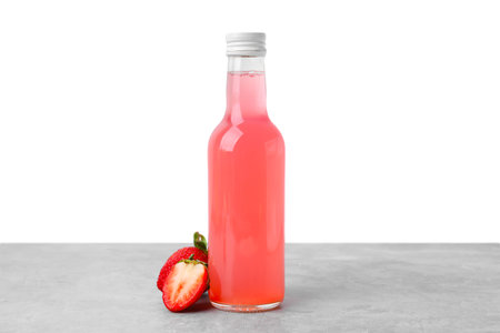 Delicious kombucha in glass bottle and strawberries on gray table against white backgroundの写真素材