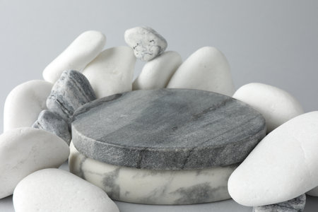 Presentation for product. Stone podium and pebbles on light gray background, closeupの写真素材