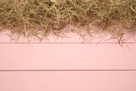 Heap of dried hay on pink wooden background, flat lay. Space for textの写真素材