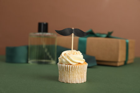 Happy Father's Day. Tasty cupcake with topper in front of presents on green table, closeupの写真素材