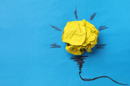 Idea concept. Light bulb made with crumpled paper and drawing on blue background, top view. Space...