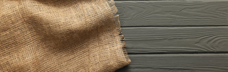 Burlap fabric on gray wooden table, top view. Space for text