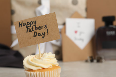 Happy Father's Day. Tasty cupcake with greetings on blurred background, closeup. Space for textの写真素材