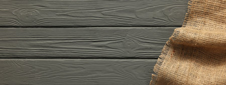Burlap fabric on gray wooden table, top view. Space for text