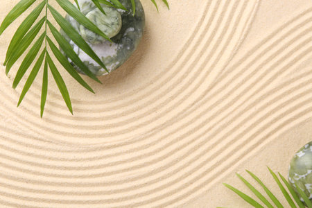Zen concept. Stones, leaves and pattern on beige sand, flat lay. Space for textの写真素材