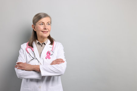 Mammologist with pink ribbon on gray background, space for text. Breast cancer awarenessの写真素材