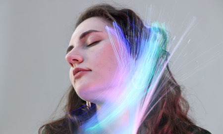 Fashionable portrait of beautiful young woman on grey background with colorful led lights
