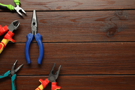 Different pliers on wooden table, flat lay. Space for text