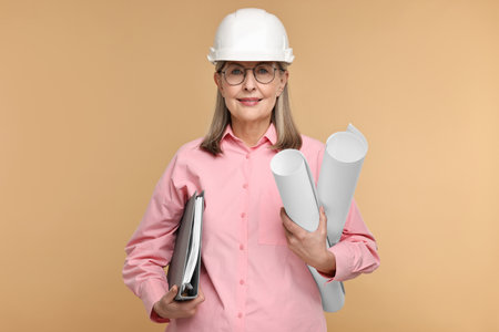 Architect in hard hat with drafts and folder on beige backgroundの写真素材
