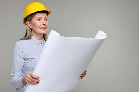 Architect in hard hat with draft on gray backgroundの写真素材