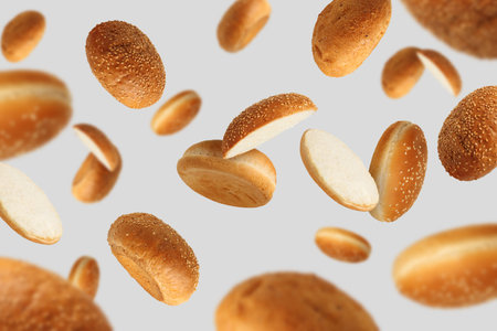 Fresh burger buns falling on light gray backgroundの写真素材