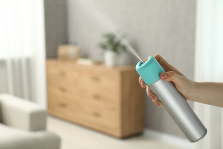 Woman spraying air freshener at home, closeup. Space for textの写真素材