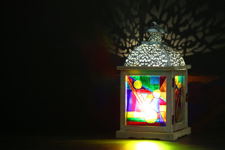 Decorative Arabic lantern on table against dark background. Space for text