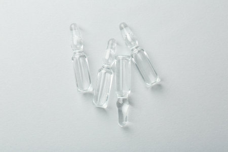 Glass ampoules with liquid on white background, top view