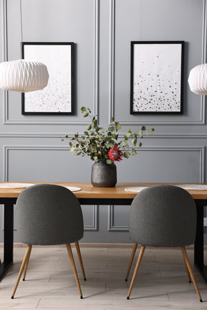 Soft chairs, table and vase with plants in stylish dining roomの写真素材