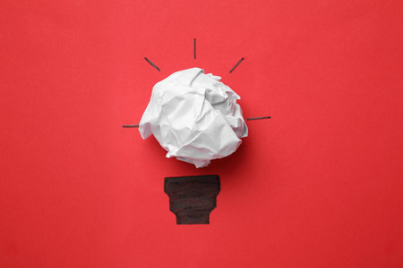 Idea concept. Light bulb made with crumpled paper and drawing on red background, top view