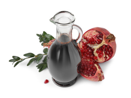 Tasty pomegranate sauce in bottle, fruits and branches isolated on whiteの写真素材
