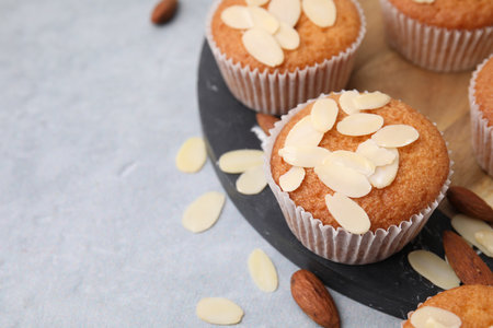 Muffins with fresh almond flakes and nuts on gray table, closeup. Space for textの写真素材