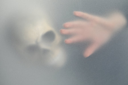 Silhouette of creepy ghost with skull behind clothの写真素材