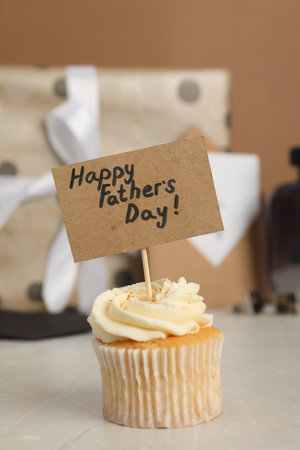 Happy Father's Day. Tasty cupcake with greetings on light table, closeupの写真素材