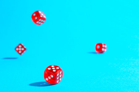 Many red game dices falling on light blue backgroundの写真素材