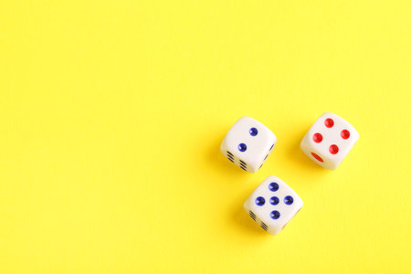 Three white game dices on yellow background, flat lay. Space for textの写真素材